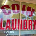 Picture of coin laundry text in red painted the front of a store